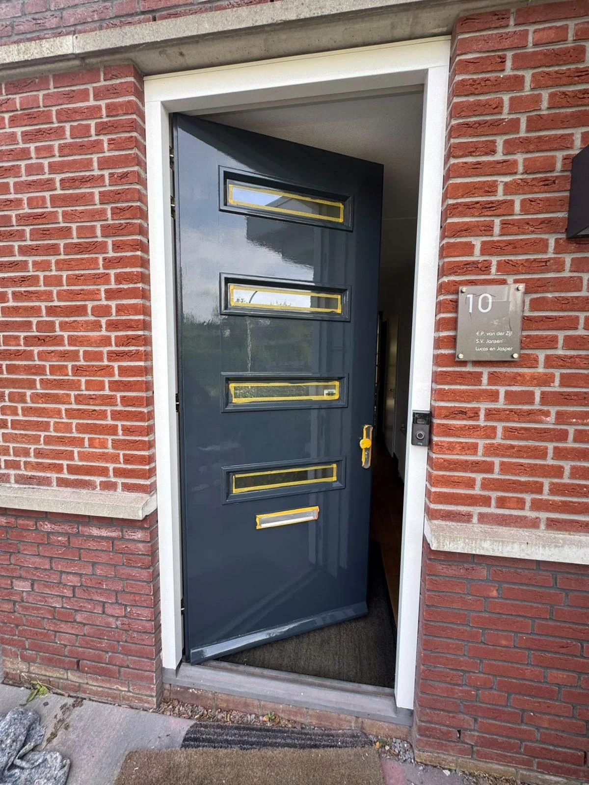 Voordeur in antraciet met glasstroken in een rode bakstenen gevel