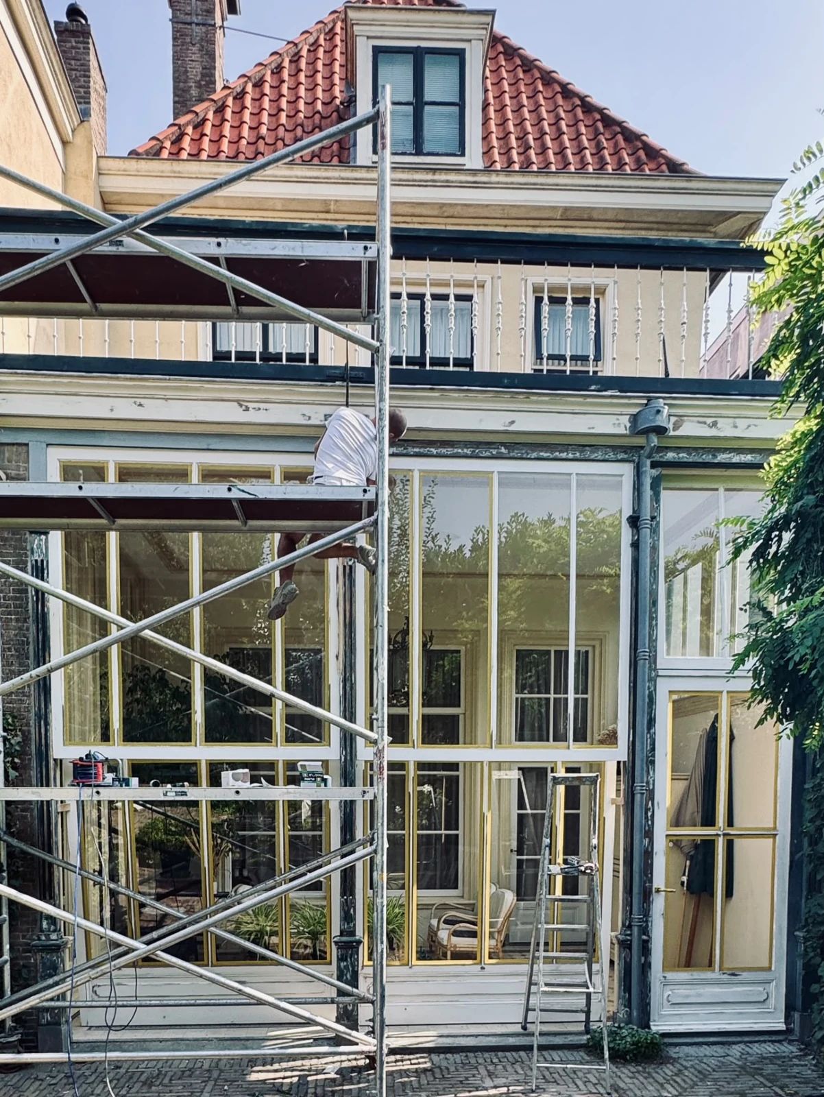 Werkzaamheden aan de gevel van een woning met een steiger voor de serre