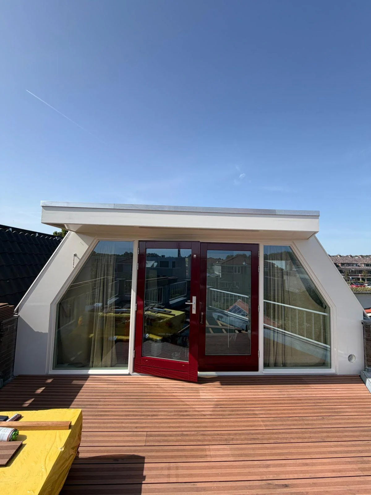 Dakopbouw met rode openslaande deuren aan een houten dakterras
