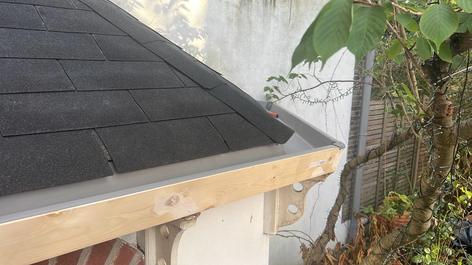Nieuwe houten daklijst en dakgoot aan een tuinhuis