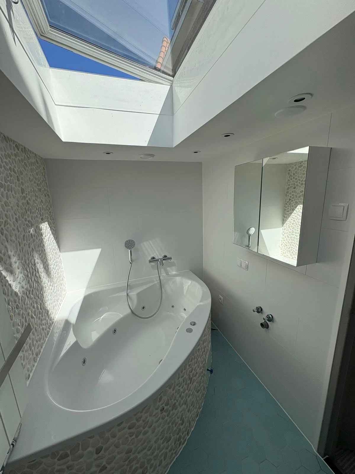 Lichte badkamer met hoekbad onder een dakraam