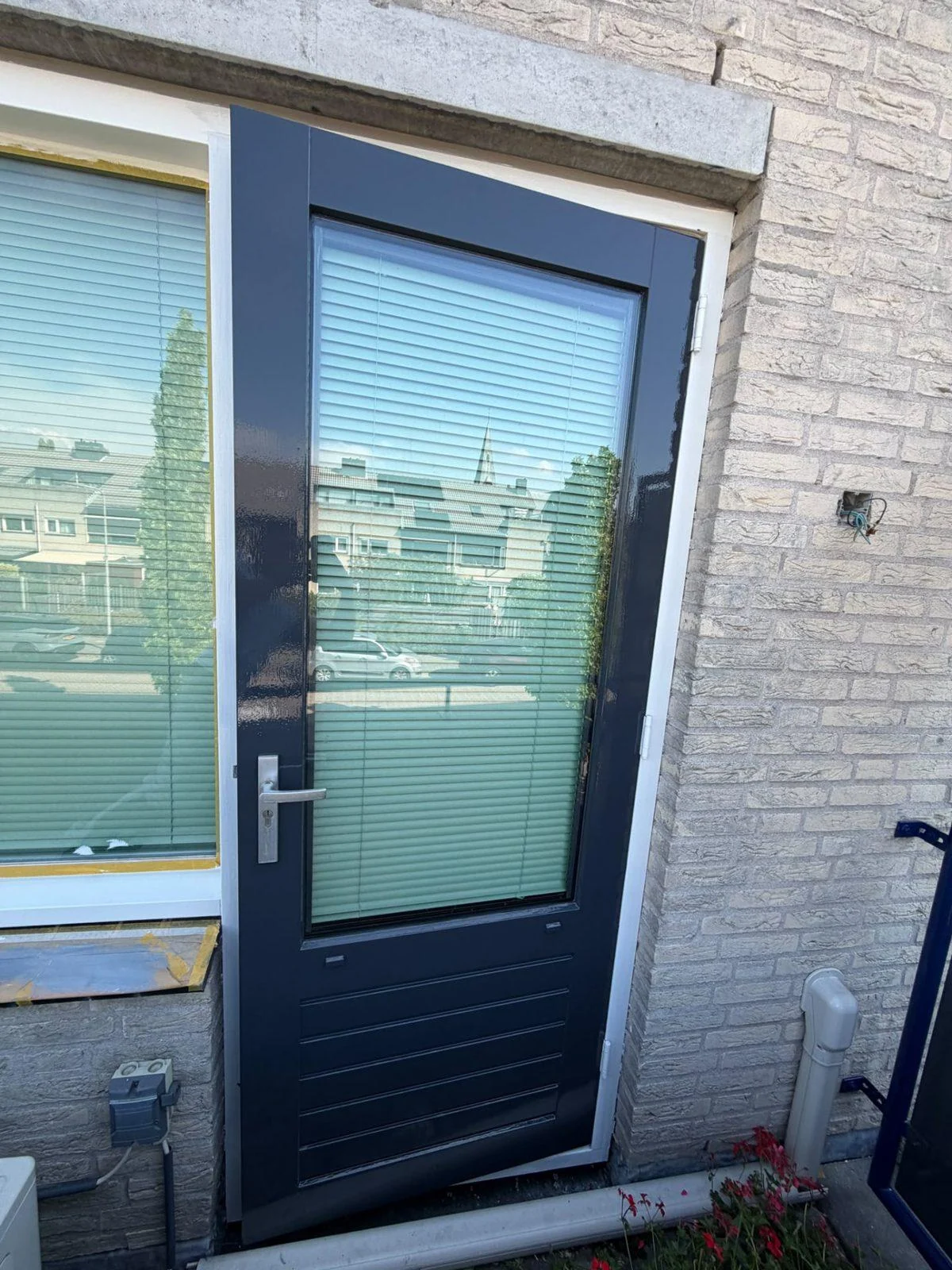 Achterdeur in antraciet met glas in een lichte bakstenen gevel